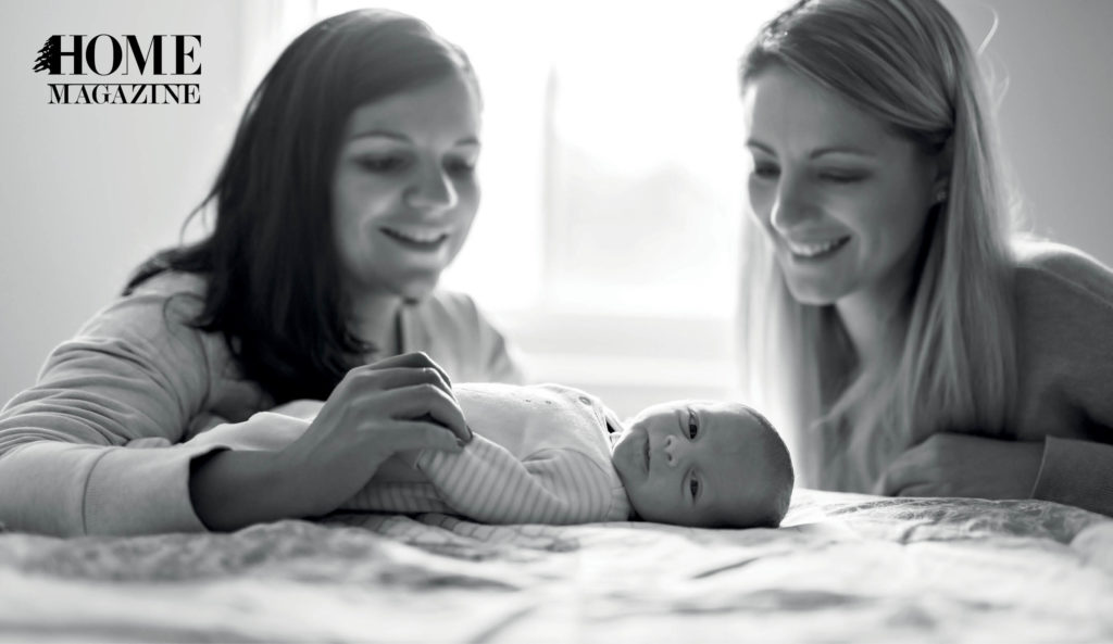 Two smiling women with newborn child