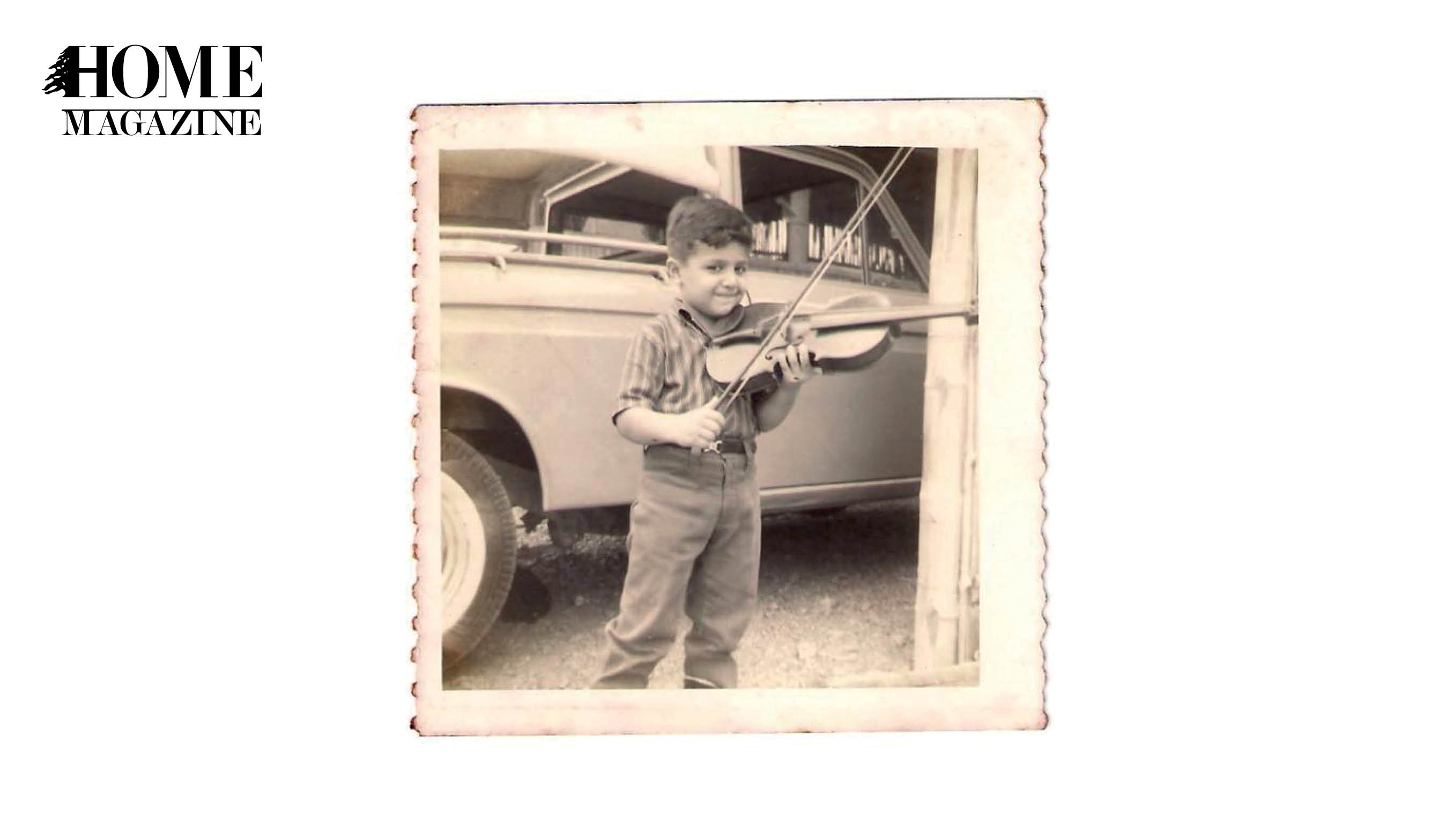Litlle boy playing violin with a car in the background