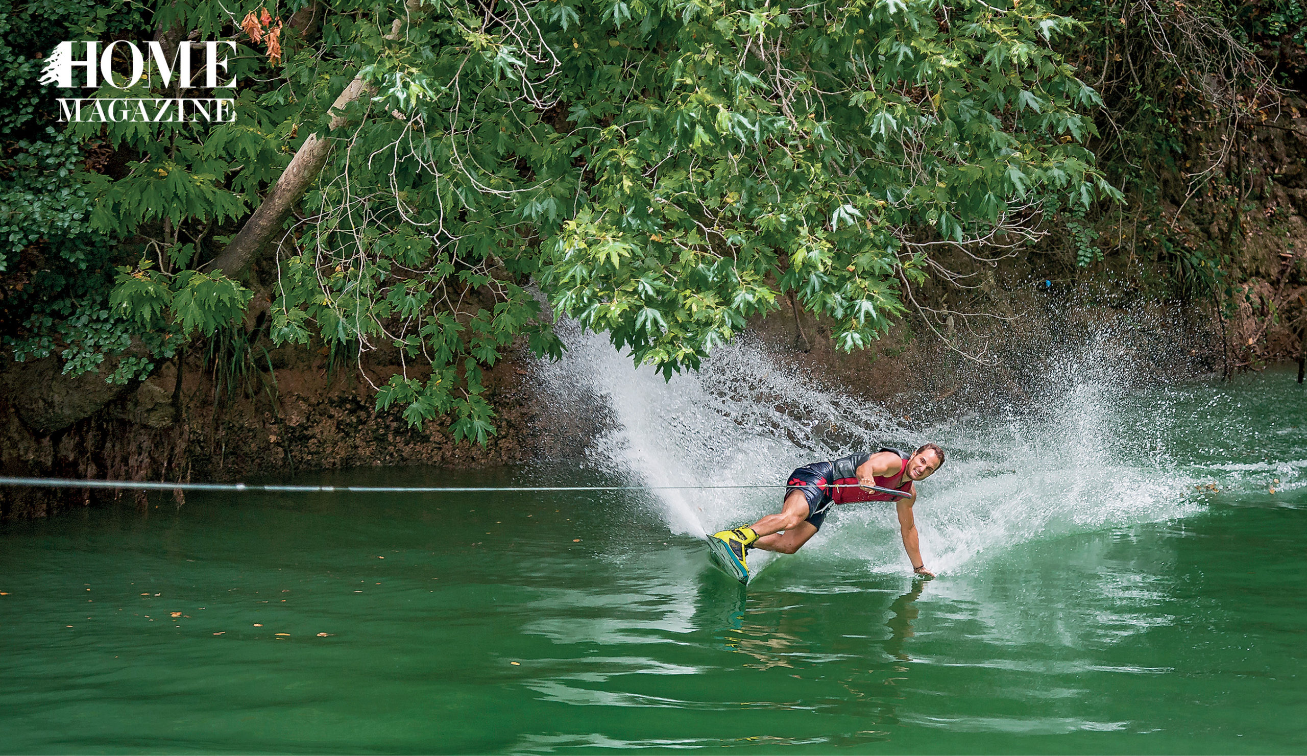 Man water surfing amidst green trees
