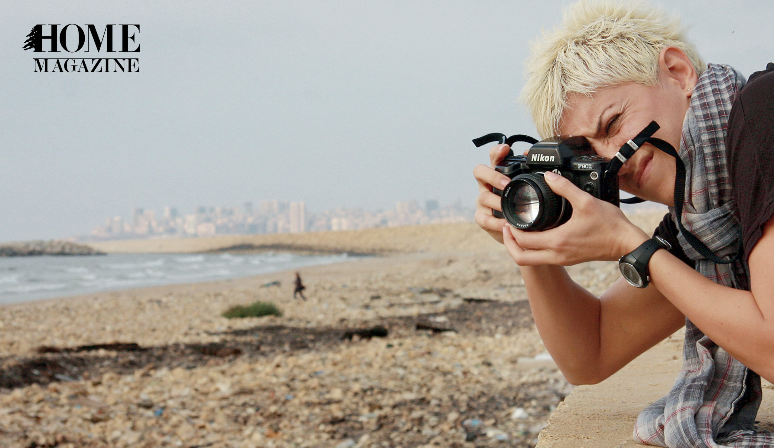 Woman with blond spike hair and scarf taking a picture with a black camera