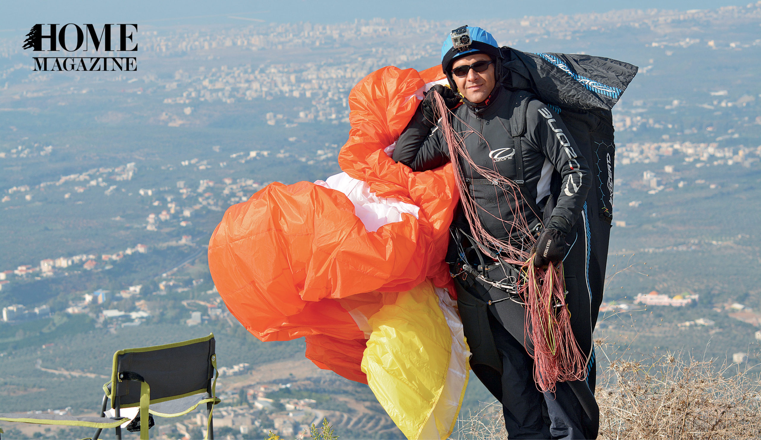 A man in black costume, helmet and sunglasses holding a foiled red and yellow parachute