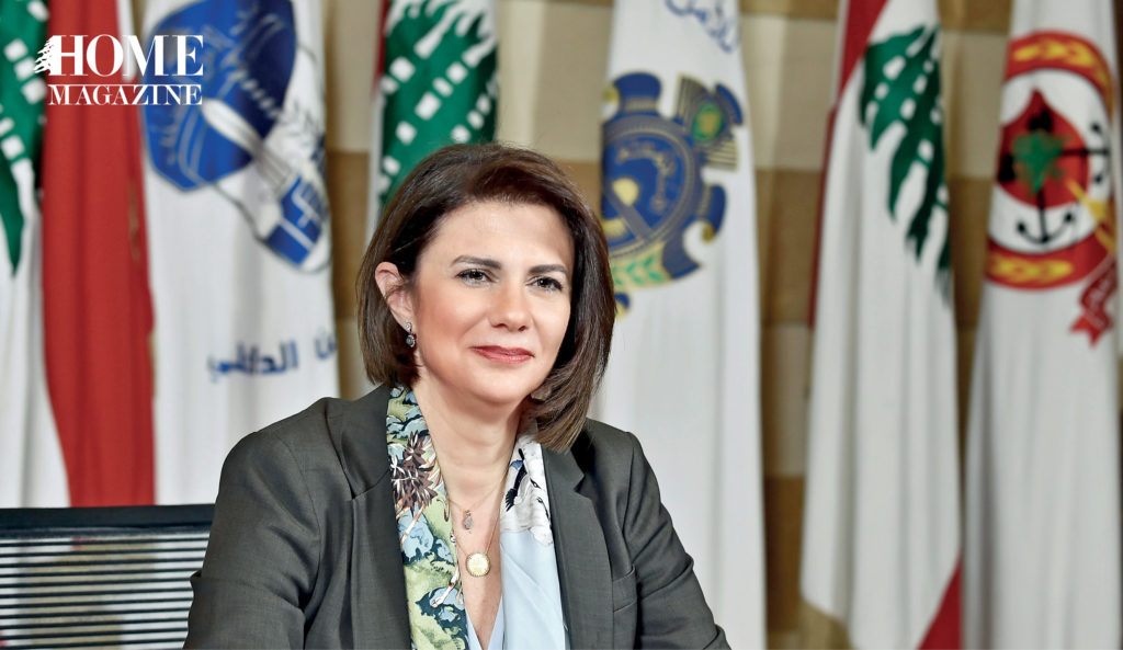 Woman in suit sitting in front of standing flags
