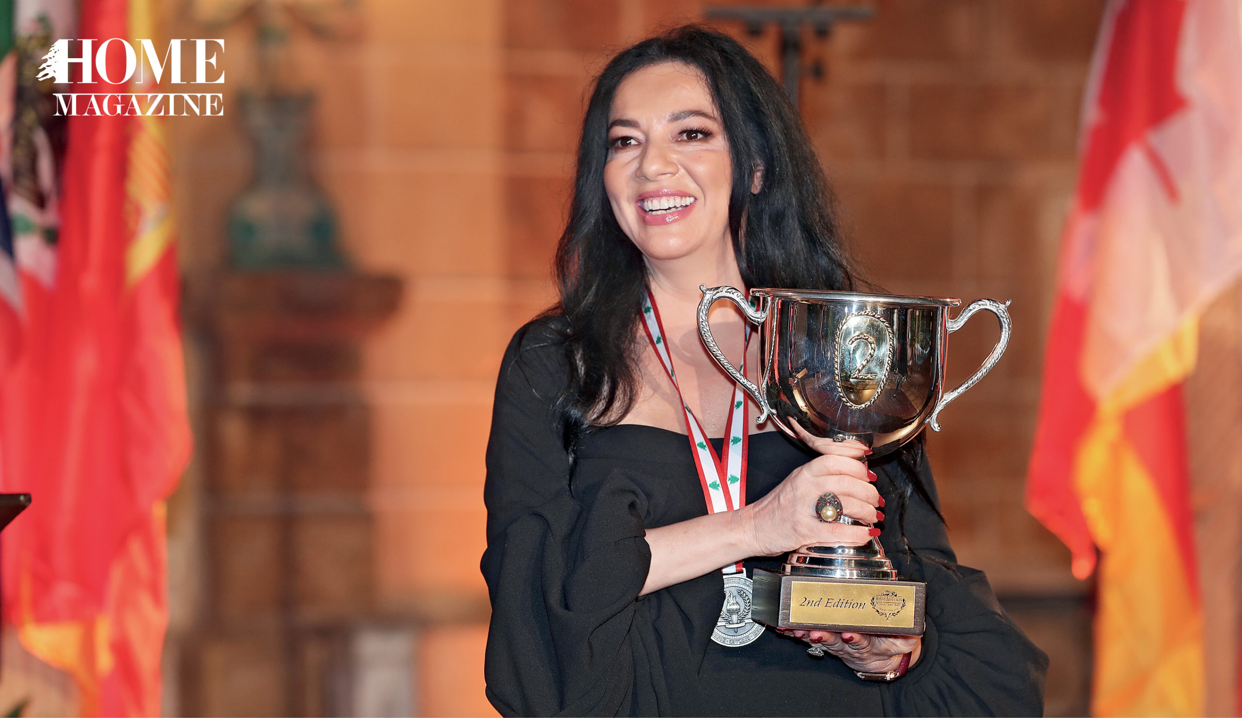 A woman with black hair and in a black dress holding a trophy and a medal around her neck